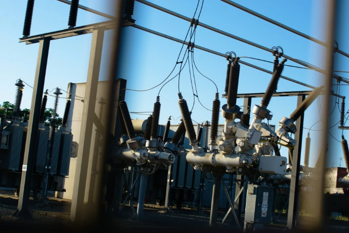 Electrical substation with transformers and power lines against blue sky.